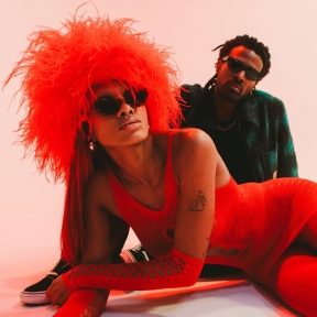 UnitedMasters Artist Floymenor in a dark red hoodie looking down to the left. 