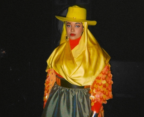 UnitedMasters Amira Unplugged in a bright yellow hat, sequenced yellow top and olive satin skirt